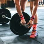 person locking gym plates on barbell