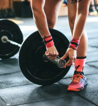 person locking gym plates on barbell